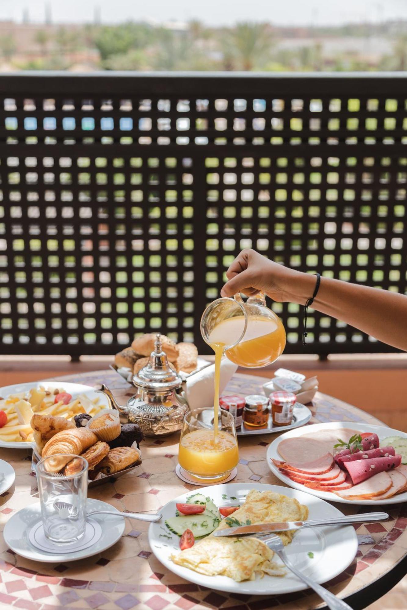 Kenzi Menara Palace & Resort Маракеш Екстериор снимка A hand pouring a glass of orange juice